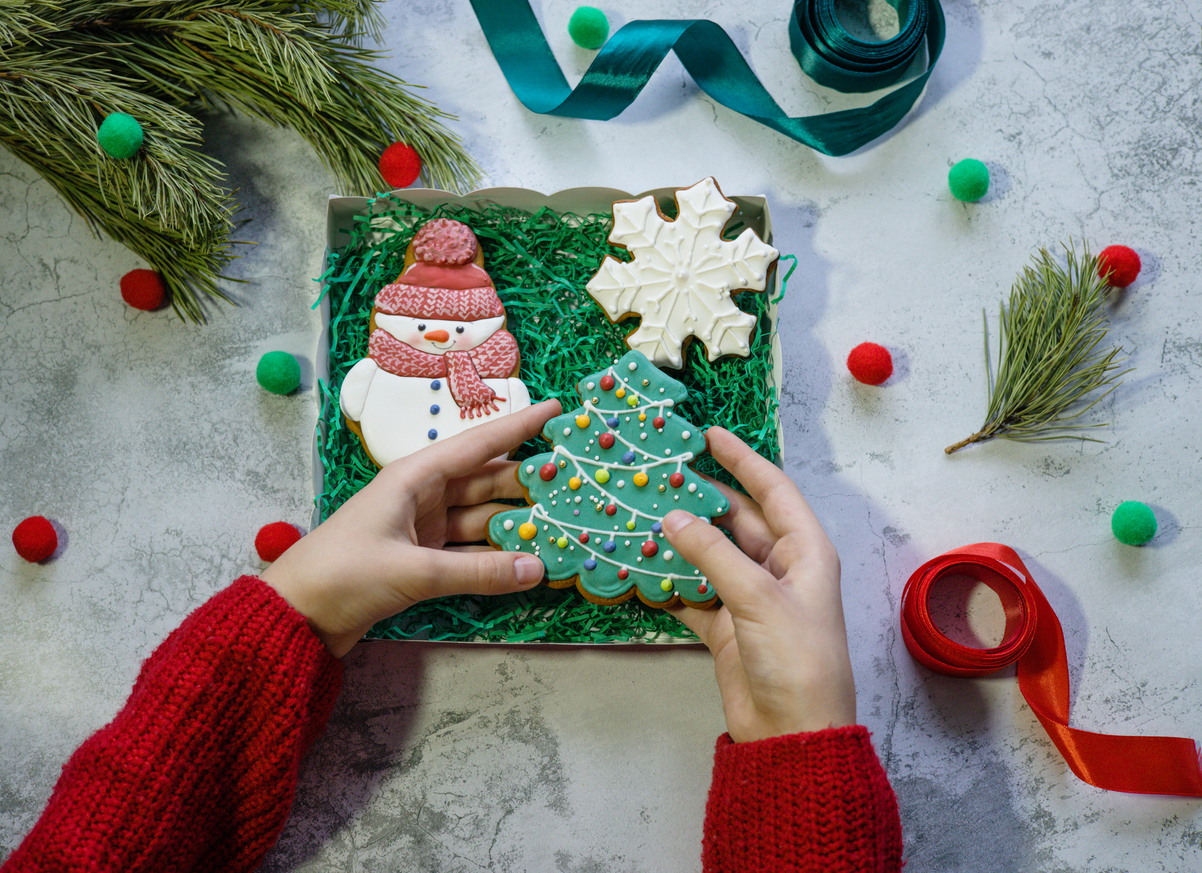 fata in pluovar rosu impacheteaza turta dulce pentru un cadou de Craciun