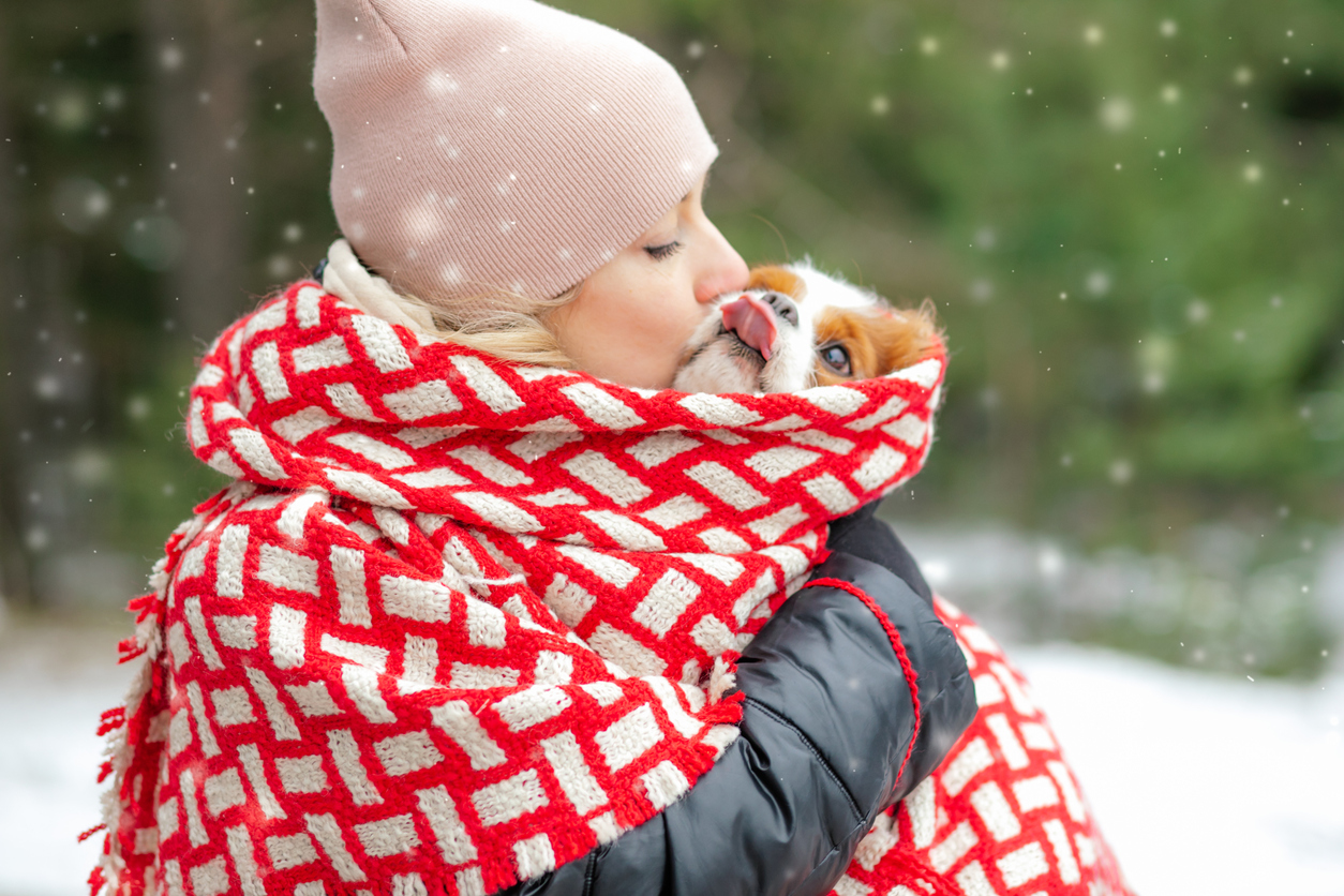 femeie care-si protejeaza cainele de frigul iernii