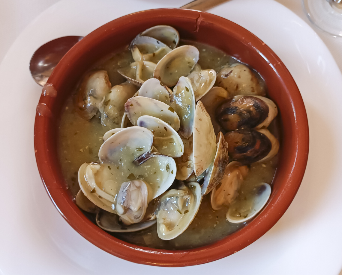 Porție delicioasă de scoici în sos de fructe de mare servită într-o oală de lut