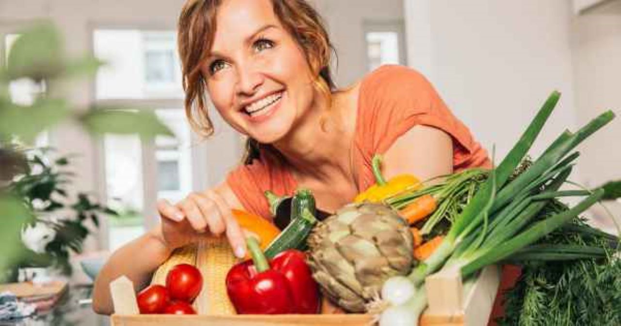 femeie la 50 de ani inconjurata de mancare sanatoasa