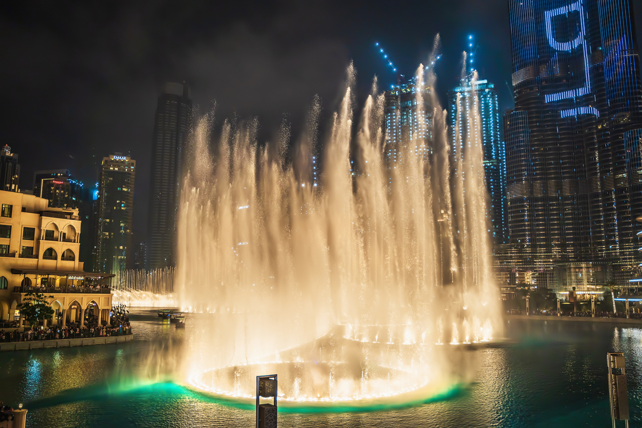 Fântână muzicală și dansatoare cu iluminare în orașul Dubai pe timp de noapte,