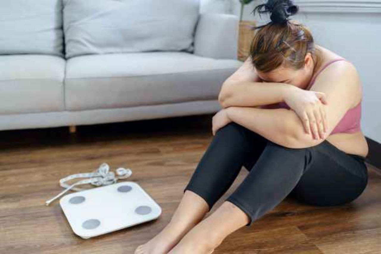 femeie ghemuita, dezamagita , alaturi de un cantar si un centimetru