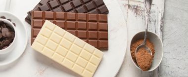 tablete de ciocolata alba, neagra , cu lapte , un bol cu banuti ciocolata si un bol cu cacao