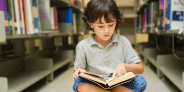 copil care citeste o carte printre rafturile unei biblioteci