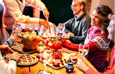 Prieteni tineri fericiți care degustă mâncare dulce de Crăciun distrându-se la petrecerea de cină acasă