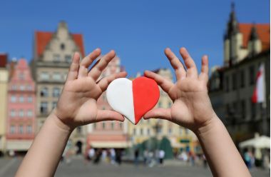 O inimă roșu-albă în culorile drapelului național al Poloniei în mâinile unui copil pe fundalul pieței orașului vechi din Polonia