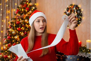 Tanara in living decorat pentru Craciun socata de pretul decoratiunilor si cadourilor de Craciu