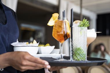 Closeup de tavă cu cocktail-uri și aperitive - Spritz și mojito servite de o chelneriță africană în barul restaurantului