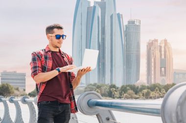 un tanar lucreaza pe laptop pe balconul unei cladiri din Dubai