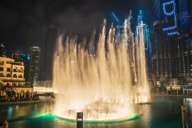 Fântână muzicală și dansatoare cu iluminare în orașul Dubai pe timp de noapte,