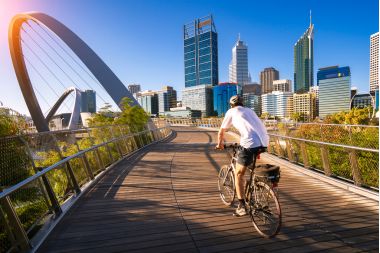 Un bărbat care merge cu bicicleta pe un pod din orașul Perth