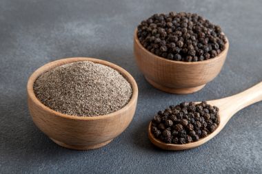 Piper negru măcinat cu boabe de piper negru pe fundal întunecat