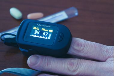 femeie care-si masoara saturatia de O cu ajutorul pulsoximetrului