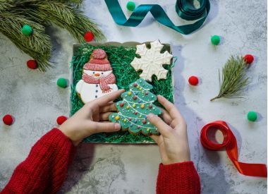 fata in pluovar rosu impacheteaza turta dulce pentru un cadou de Craciun