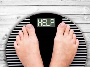 femeie care sta pe un cantar ce afiseaza mesajul help