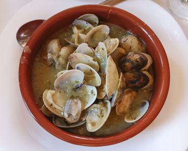 Porție delicioasă de scoici în sos de fructe de mare servită într-o oală de lut